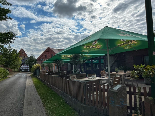 Terrasse Cafe Weserscheune Außenterrasse eines Cafés mit charakteristischen Ziegelgebäuden, aufgestellten Sonnenschirmen und Holzzaun.
