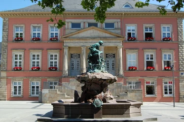 Bronzefigur des Donopbrunnens vor dem historischen Gebäude des Detmolder Marktplatzes.