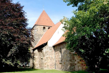 Historische Kirche in Petershagen mit Feldsteinmauerwerk, rotem Ziegeldach und Baumkulisse.