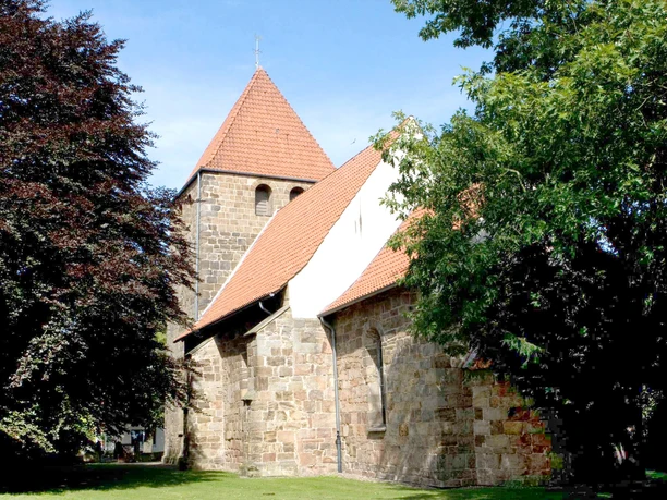 Stadt Petershagen Historische Kirche in Petershagen mit Feldsteinmauerwerk, rotem Ziegeldach und Baumkulisse.