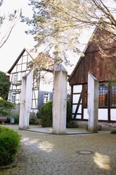 Gedenkstätte für die Opfer der nationalsozialistischen Gewaltherrschaft in Detmold, hinter der alten Synagoge Gedenkstätte mit vier minimalistisch gestalteten Stelen aus hellem Stein, umgeben von Fachwerkbauten.