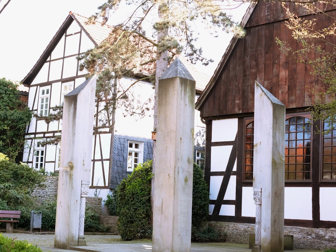 Gedenkstätte für die Opfer der nationalsozialistischen Gewaltherrschaft in Detmold, hinter der alten Synagoge Gedenkstätte mit vier minimalistisch gestalteten Stelen aus hellem Stein, umgeben von Fachwerkbauten.
