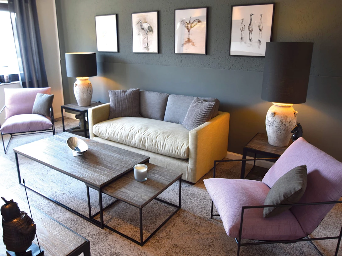 BESOTEL Erkrath Ein stilvoll eingerichtetes Wohnzimmer mit modernen Möbeln und künstlerischen Akzenten an den Wänden.