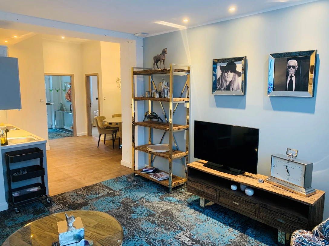 Besotel Mettmann Modern eingerichtetes Wohnzimmer mit hellen Wänden, einem großen Fernseher und stilvollen Dekorationen.