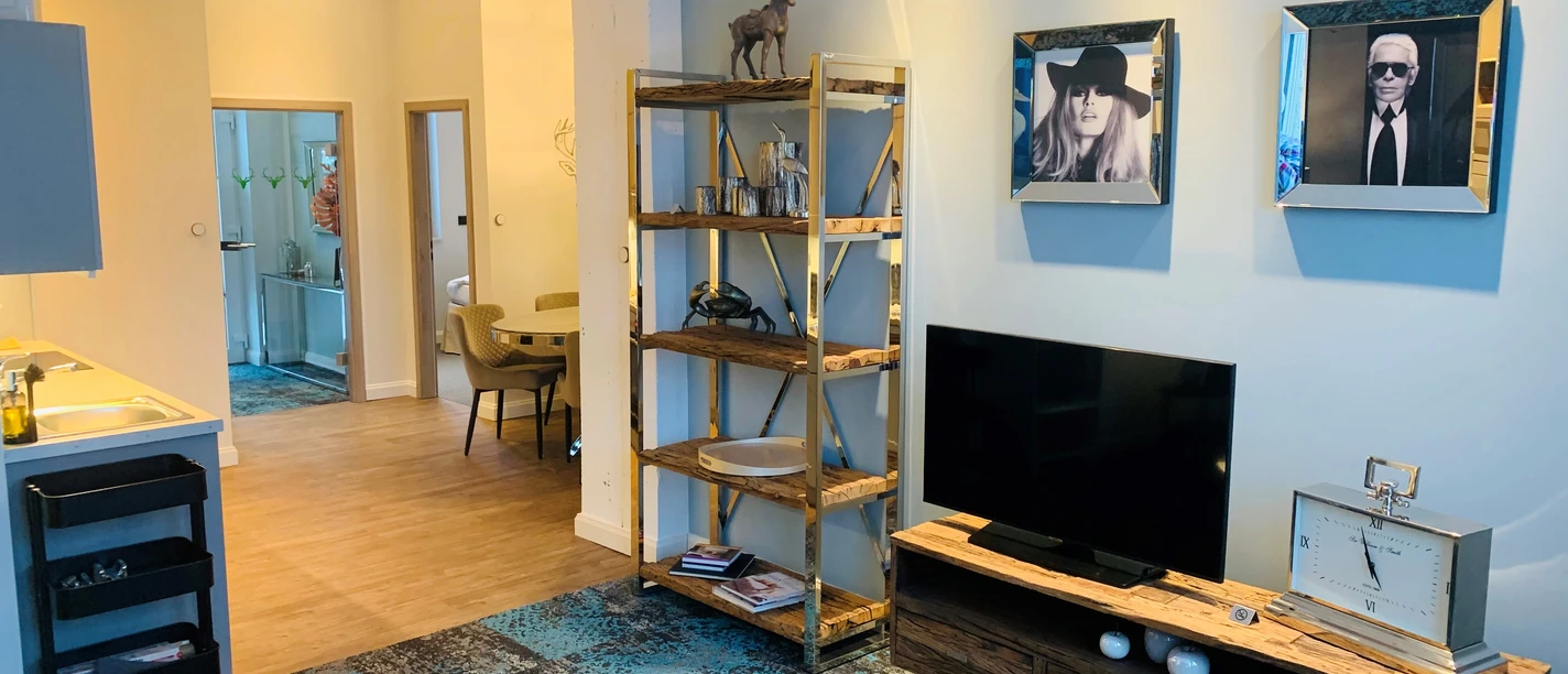 Besotel Mettmann Modern eingerichtetes Wohnzimmer mit hellen Wänden, einem großen Fernseher und stilvollen Dekorationen.