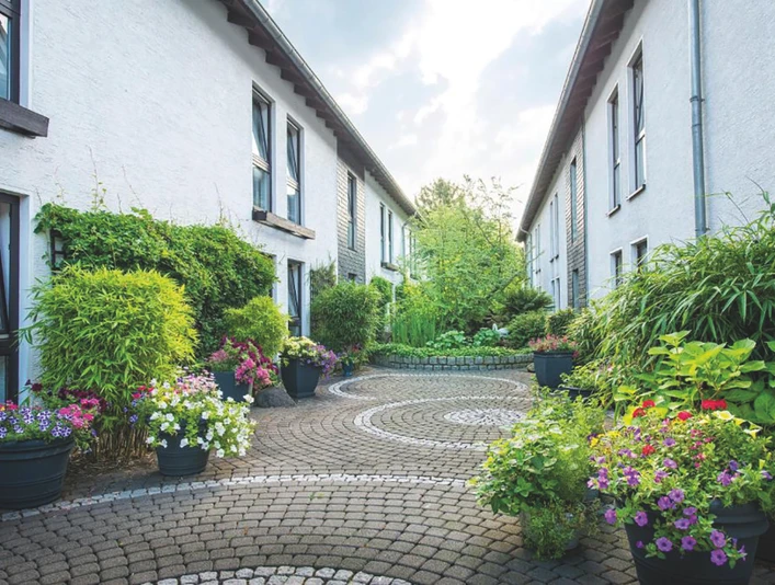 Hotel am Wald in Mohnheim am Rhein Gepflegter, mit Pflanzen gesäumter Innenhof zwischen zwei weißen Gebäuden, entspannende Atmosphäre.
