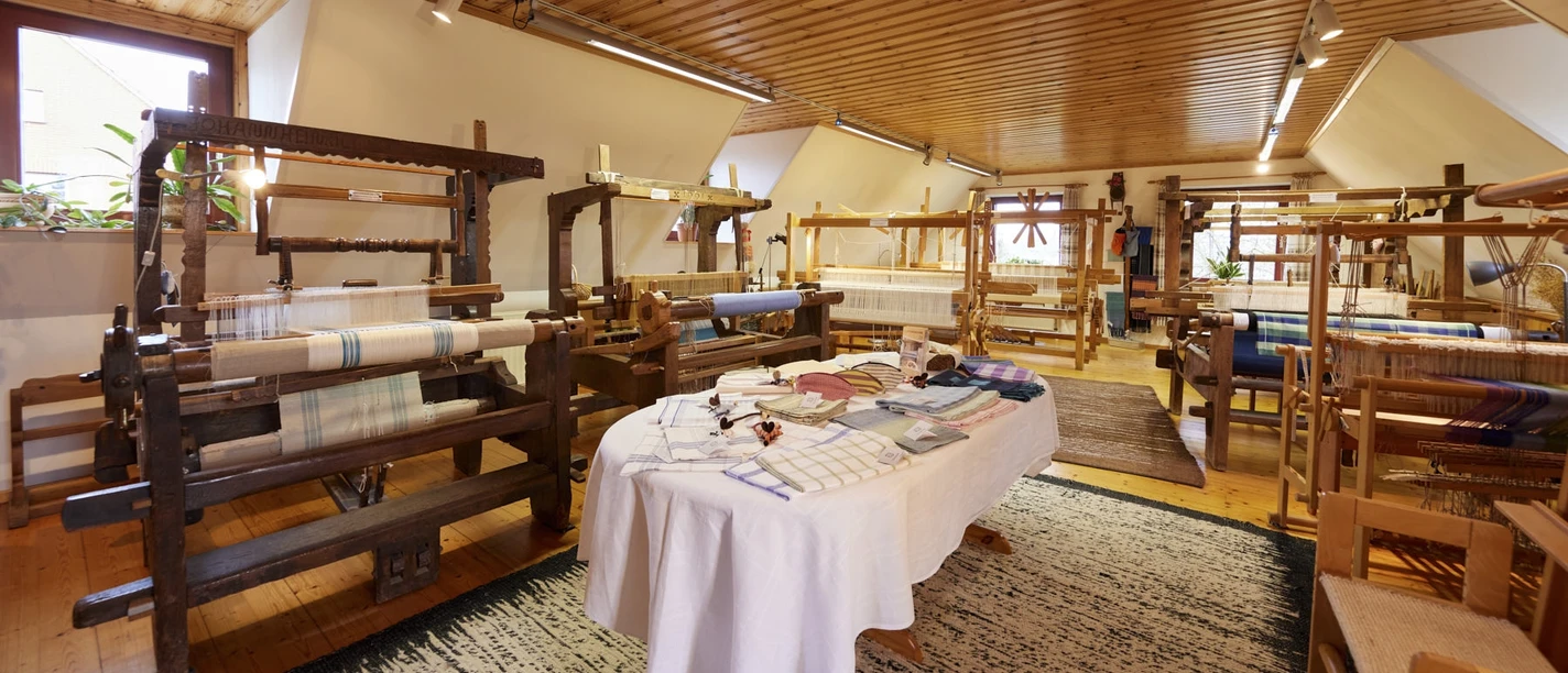 Webstube Ilse In einem lichtdurchfluteten Raum stehen mehrere historische Webstühle auf einem Holzfußboden.