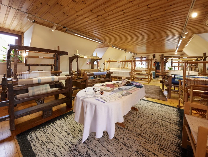 Webstube Ilse In einem lichtdurchfluteten Raum stehen mehrere historische Webstühle auf einem Holzfußboden.