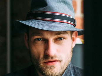 Grauer Herrenhut von Gela-Hüte - Regionale Produkte Ein Mann trägt einen grauen Hut mit schwarz-rotem Hutband von Angela Wandelt aus der Hutmanufaktur Gela-Hüte in der Spinnerei Leipzig Plagwitz, regionale Produkte
