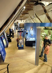 Storchenmuseum Innenansicht des Storchenmuseums: Besucher erkunden verschiene Exponate in einem rustikalen Raum.