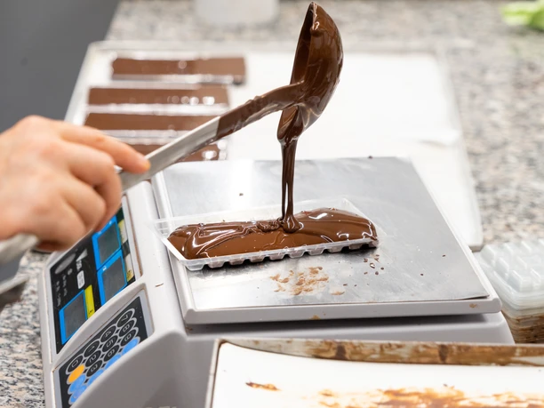 Schokoladentafel der Chocolaterie Praetsch - Regionale Produkte Auf einer Waage wird eine Schokoladentafel der Chocolaterie Praetsch in Wermsdorf händsich gegossen und abgewogen, regionale Produkte