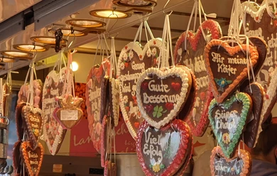 Herzförmige Lebkuchen mit buntem Zuckerguss hängen an einem Verkaufsstand auf der Kirmes.