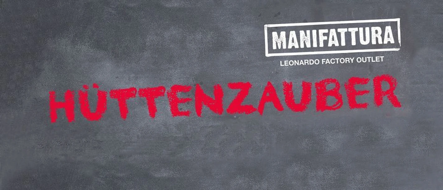 Hüttenzauber in der MANIFATTURA Große weiße Tafel mit dem Schriftzug "MANIFATTURA" und rotem darunterliegendem Wort "HÜTTENZAUBER".
