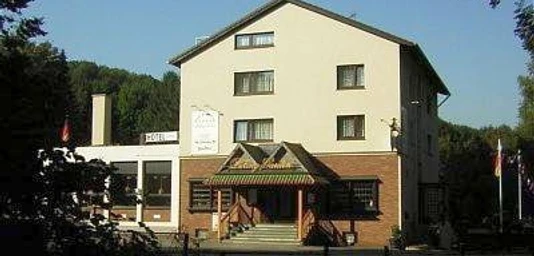 Hotel Talburg in Heiligenhaus Vierstöckiges, rechteckiges Hotelgebäude mit hellem Anstrich, umgeben von Bäumen, Eingang mit Vordach.