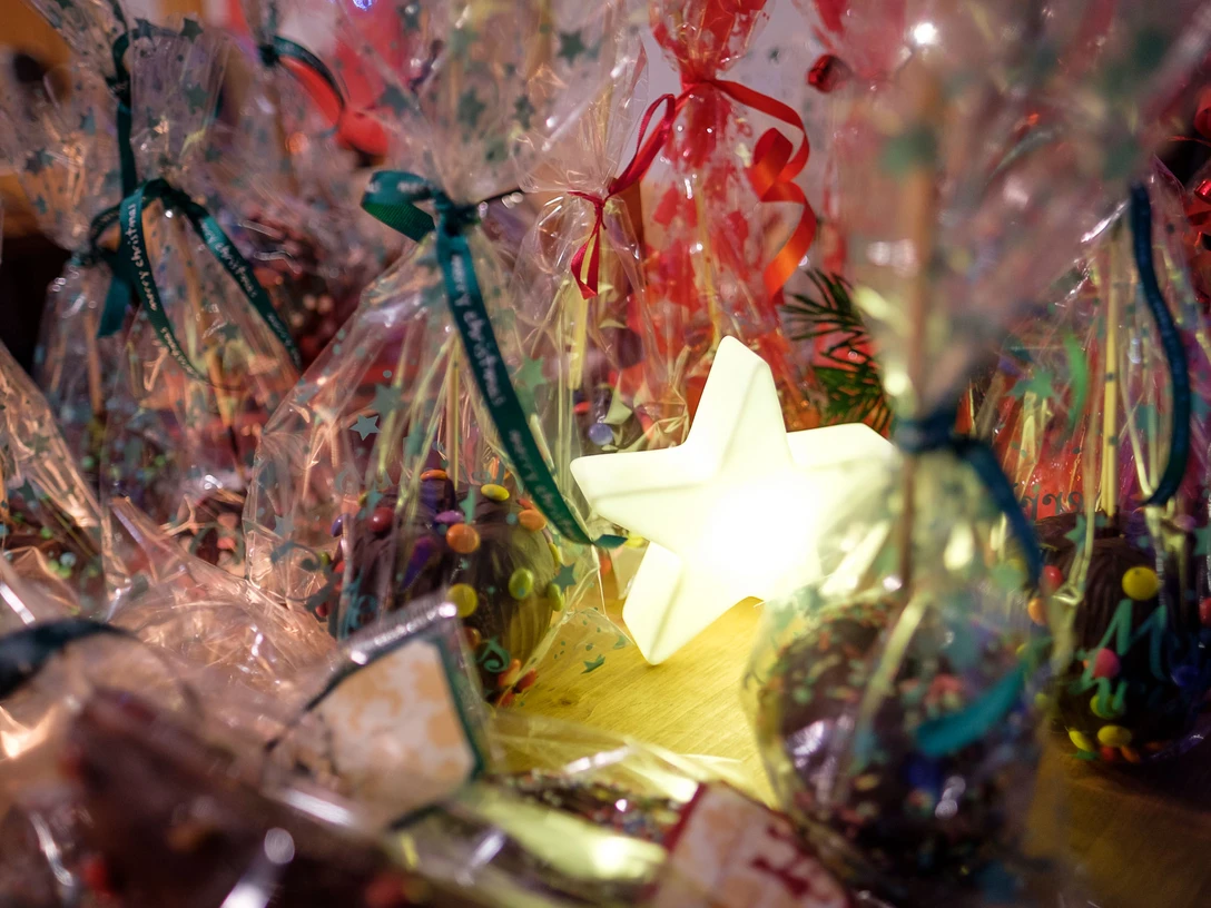 Festliche Plätzchen in bunten Tütchen, umrahmt von leuchtendem Stern, schaffen weihnachtliche Atmosphäre.