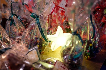 Festliche Plätzchen in bunten Tütchen, umrahmt von leuchtendem Stern, schaffen weihnachtliche Atmosphäre.