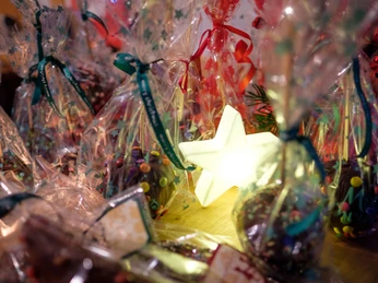 Adventsplaetzchen.jpg Festliche Plätzchen in bunten Tütchen, umrahmt von leuchtendem Stern, schaffen weihnachtliche Atmosphäre.