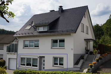 Aussenansicht Zweistöckiges Wohnhaus mit grauem Dach, weißen Wänden, mehreren Fenstern und seitlichen Treppen.