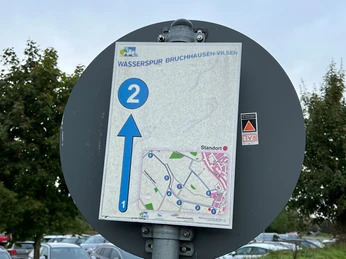 Wasserspur Bruchhausen-Vilsen Wegweiser an einem Rundwanderweg mit Karte und Pfeil. Ziel Bruchhausen-Vilsen, Punkt zwei markiert.