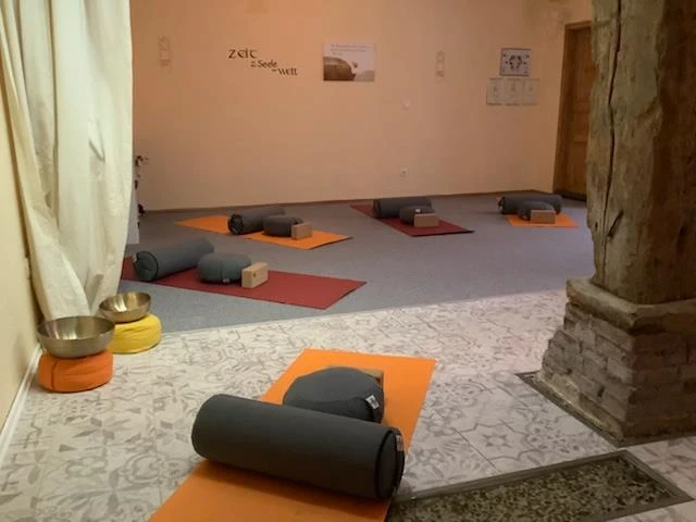 Yoga in der Natur-Klang-Raum Praxis im Spiegelhaus Woltzeten Yogaraum mit Matten, Bolstern und Klangschalen, sanft beleuchtet für Meditation und Entspannung.