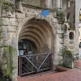WunstorfInfo01.jpg Historischer Eingang zur Stadtbücherei mit Rundbogen und alten Steinverzierungen in einer urbanen Umgebung.