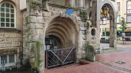 Eingang zur Stadtbibliothek Wunstorf mit steinernen Rundbögen und historischer Architektur im Hintergrund.