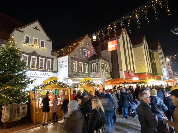 Weihnachtsmarkt in Lübbecke mit leuchtenden Ständen, festlicher Beleuchtung und einer Menschenmenge.