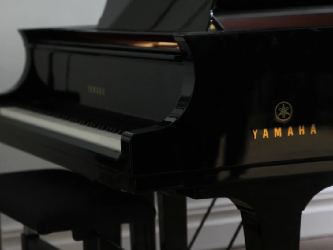 Klavier-piano-pixabay Ein schwarzer Flügel der Marke Yamaha steht in einem lichtdurchfluteten Raum neben einem Hocker.