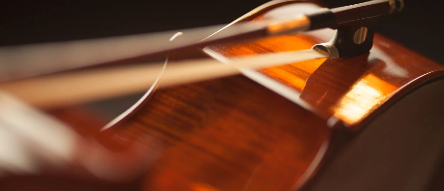 Nahaufnahme einer Violine mit fokussiertem Licht auf dem Korpus und einem darauf liegenden Bogen.