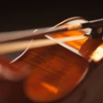 Violine Nahaufnahme einer Violine mit fokussiertem Licht auf dem Korpus und einem darauf liegenden Bogen.
