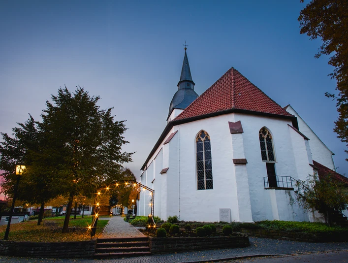 Levern, Stemwede: Historische Kirche bei Sonnenaufgang, umgeben von prachtvoller Herbstlandschaft.
