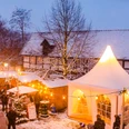 Stemwede-Levern Weihnachten Weihnachtsmarkt in Stemwede-Levern bei Schneefall, mit Lichtern, Ständen und einem weißen Zelt.