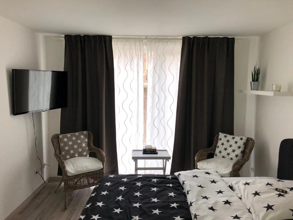 Pension Osthoff Wülfrath Zimmer der Pension Osthoff Wülfrath mit modernen Möbeln, TV, zwei Stühlen und dunklen Vorhängen.