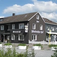 Hotel-Restaurant Windrather Hof in Velbert Ein traditionelles Fachwerkgebäude mit weißen Fensterrahmen und detaillierten Holzarbeiten.