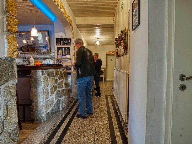 bei-nico-griechisches- restaurant-amelinghausen-tressen Tresenbereich im Restaurant Bei Nico mit Natursteinverkleidung und Gästen im Gang.