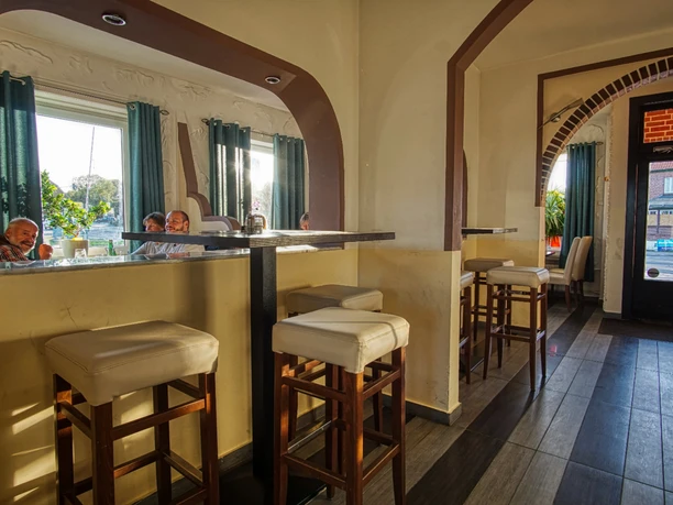 Gastraum des Restaurants Terrazza Heller Gastraum mit hohen Bartischen, gepolsterten Hockern und Blick auf weitere Sitzbereiche.