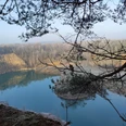 Steinbruch mit See Geopark mit See und Bäumen, ruhige Wasseroberfläche und bewaldete Ufer im Hintergrund.
