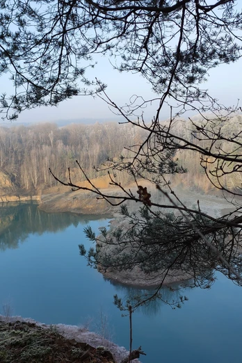 Steinbruch mit See Geopark mit See und Bäumen, ruhige Wasseroberfläche und bewaldete Ufer im Hintergrund.Geopark with lake and trees, calm water surface and wooded banks in the background.Geopark med sø og træer, rolig vandoverflade og skovklædte bredder i baggrunden.Geopark met meer en bomen, rustig wateroppervlak en beboste oevers op de achtergrond.