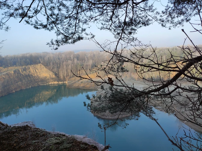 Steinbruch mit See Geopark mit See und Bäumen, ruhige Wasseroberfläche und bewaldete Ufer im Hintergrund.Geopark with lake and trees, calm water surface and wooded banks in the background.Geopark med sø og træer, rolig vandoverflade og skovklædte bredder i baggrunden.Geopark met meer en bomen, rustig wateroppervlak en beboste oevers op de achtergrond.