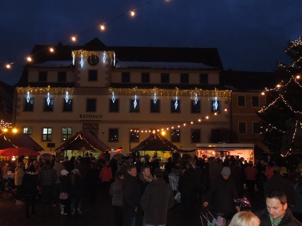 Hoyerswerda.JPG Weihnachtsmarkt vor dem Rathaus von Hoyerswerda in der Abenddämmerung mit beleuchteten Ständen.