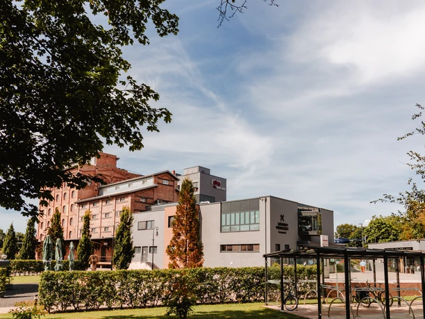 PS.SPEICHER Historischer Backsteinbau und moderner Anbau des Museums PS.SPEICHER hinter grünen Hecken.