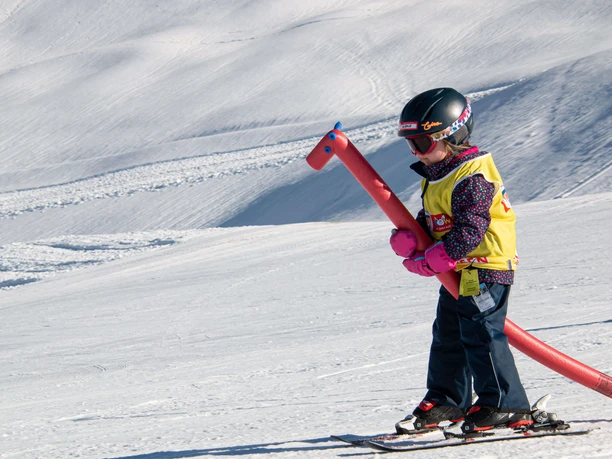 In der Skischule Skifahren lernen Kind auf Skis mit rotem Steckenpferd