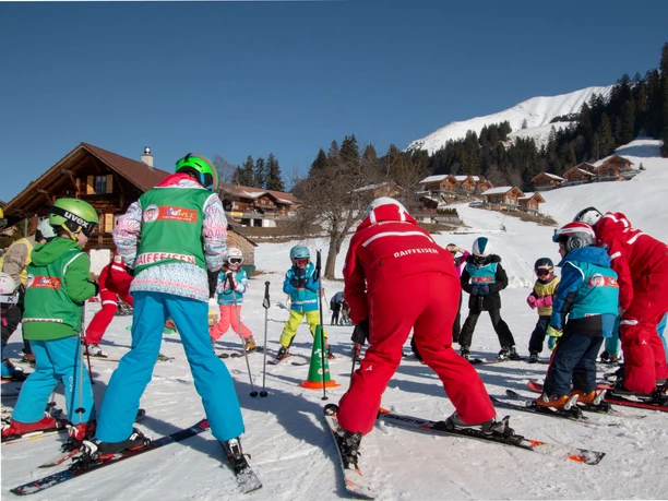 S'échauffer avant les cours de l'école de ski Moniteur de ski et élèves skieurs debout en cercle effectuant des exercices d'échauffement.