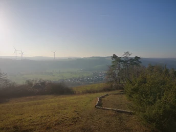 Landschaftspanorama vom Stockberg aus mit Blick auf das weitläufige Tal und Windräder im Hintergrund.