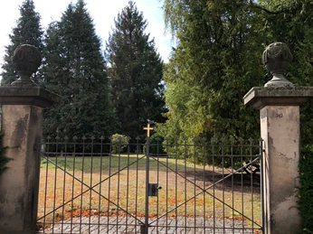 Alter Friedhof Neustadt Eisernes Tor führt zu einem historischen Friedhof, umgeben von hohen Bäumen und herbstlichem Laub.