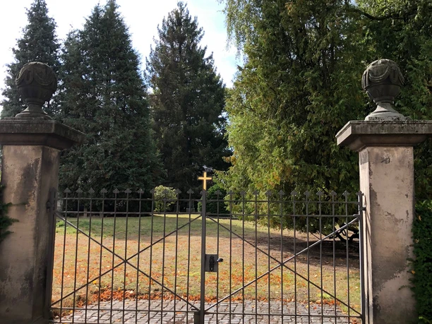 Alter Friedhof Neustadt Eisernes Tor führt zu einem historischen Friedhof, umgeben von hohen Bäumen und herbstlichem Laub.