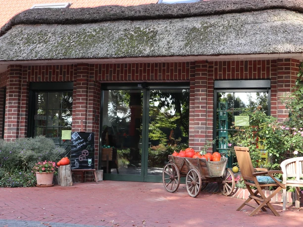 Ein Backsteinhaus mit Strohdach, dekoriert mit Kürbissen und Blumen, vermittelt ländliche Idylle.