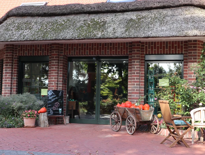 Ein Backsteinhaus mit Strohdach, dekoriert mit Kürbissen und Blumen, vermittelt ländliche Idylle.