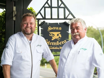 Sterneküche Haus Stemberg in Velbert Zwei Köche in weißer Kleidung stehen vor einem Schild des renommierten Haus Stemberg in Velbert.