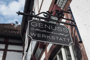 Genusswerkstatt exterior Schild der "Genusswerkstatt Mallinckrodthof", angebracht an einer Fachwerkfassade, zeigt den Namen.